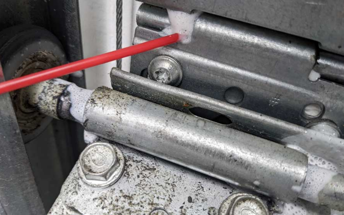An image of a technician using tools to fix a noisy garage door in a residential driveway, emphasizing professional repair services in Dublin.
